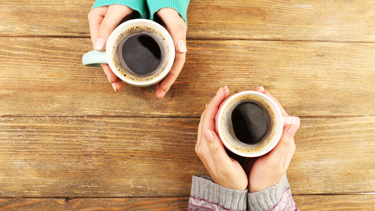 Shutterstock photo of two female hands holding cups of coffee