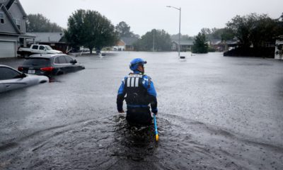 Photo of a member of the North Carolina Task Force search and rescue team wading through flooded neighborhoods