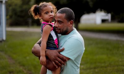 Photo of Jose Perez-Santiago, right, holding his daughter Jordalis, 2, as they return to their home for the first time since it was flooded