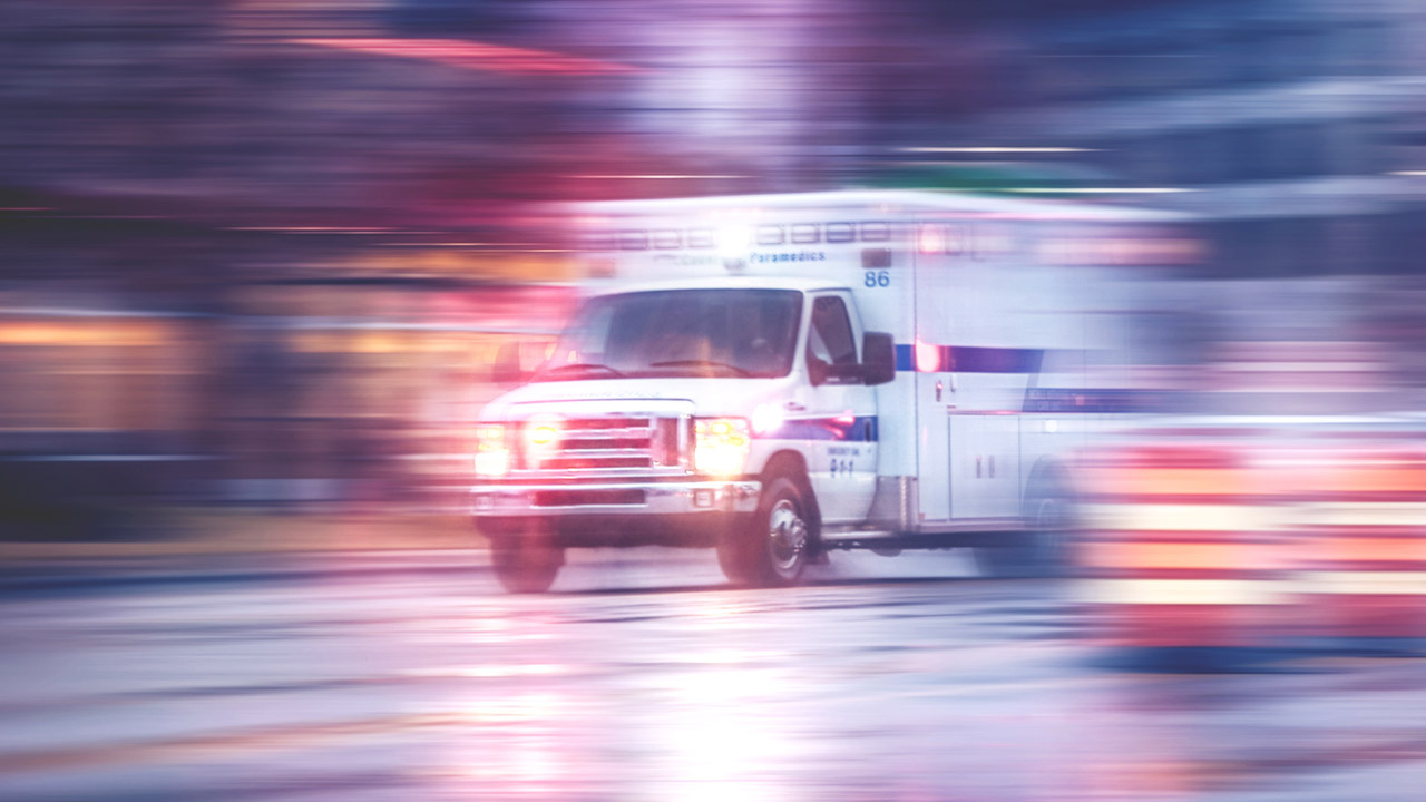 Photo of ambulance racing through city streets on a rainy night