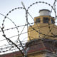 A prison guard tower viewed through razor wire fencing