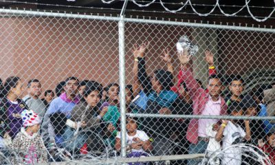 Photo of migrant families behind a barbed wire fence