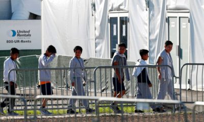 Photo of children lining up to enter a tent at the Homestead Temporary Shelter for Unaccompanied Children in Homestead, Fl.