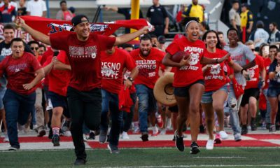 Photo of Fresno State students running onto the football field