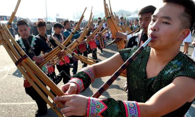 Photo of Phia Chia performing on a traditional Hmong instrument, the qeej