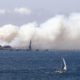 Photo of yacht sailing past a burning woodchip mill