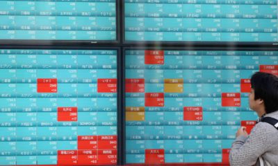 Photo of a man looking at an electronic stock board of a securities firm in Tokyo