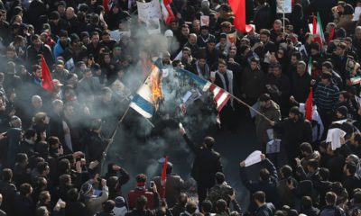 Photo of mourners burning mock flags of the U.S. and Israel during a funeral ceremony for Iranian Gen. Qassem Soleimani