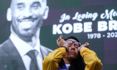 Photo of a woman wiping tears from her eyes at a Kobe Bryant memorial at the Staples Center in Los Angeles