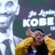 Photo of a woman wiping tears from her eyes at a Kobe Bryant memorial at the Staples Center in Los Angeles