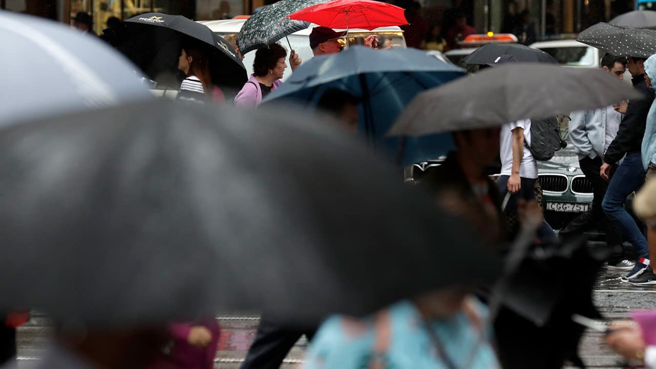 Photo of people sheltering under umbrellas in Australia