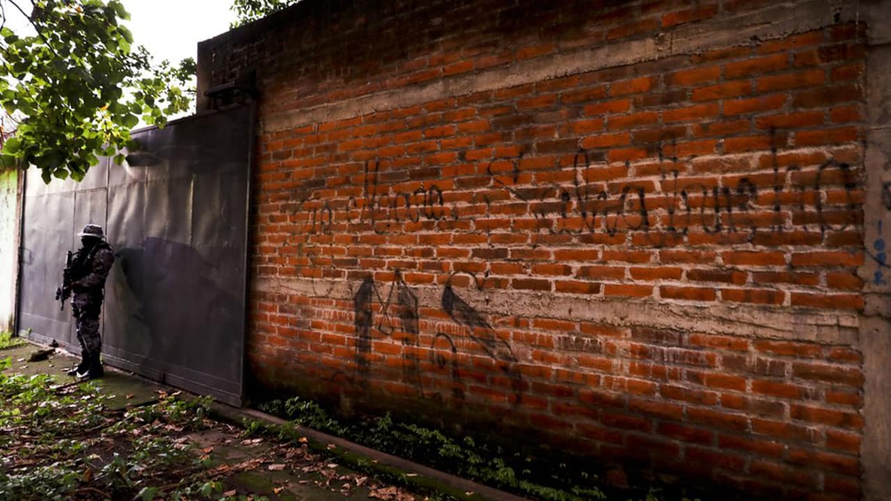 Photo of a police guard next to a graffiti wall in El Salvador