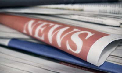 Photo of newspapers stacked up with the word "news" showing