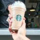 Image of a Starbucks employee handing a frappe mocha latte to a customer at drive thru counter.