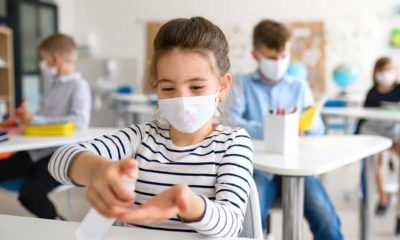 Image of a young student in a mask sanitizing her hands amid the coronavirus pandemic