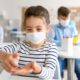 Image of a young student in a mask sanitizing her hands amid the coronavirus pandemic