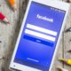 Photo of smartphone opened to Facebook sign-in page surrounded by colored pencils