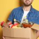 Picture of a young man carrying a box of donated groceries