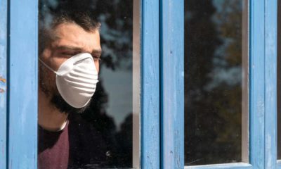 Image of a patient with a mask looking out of a hospital window