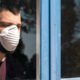 Image of a patient with a mask looking out of a hospital window