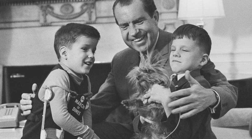 FILE – In this Feb. 5, 1969, file photo President Richard Nixon smiles as he shows off one of the White House pets tiny Yorkshire terrier Pasha to two junior visitors in his office in Washington. His guests are five-year-old Tracy Greenwood, the March of Dimes National Poster Child, and his 7-year-old brother Jamie. (AP Photo, File)