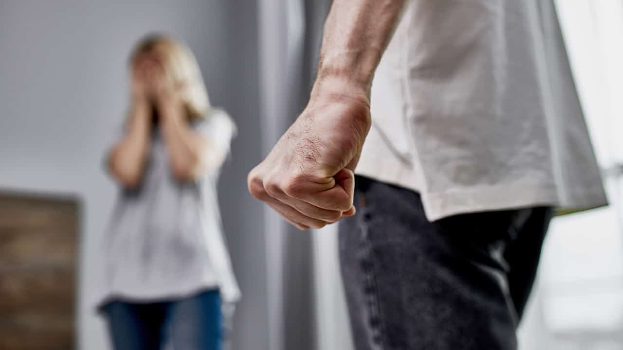 Photo of a man with a balled first near a woman symbolizing domestic violence